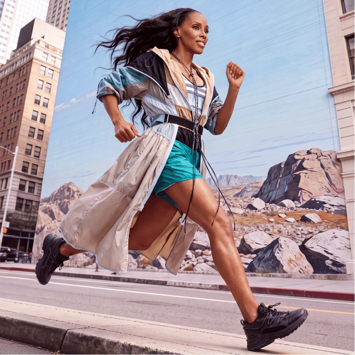 Woman running down a city street wearing black sneakers.